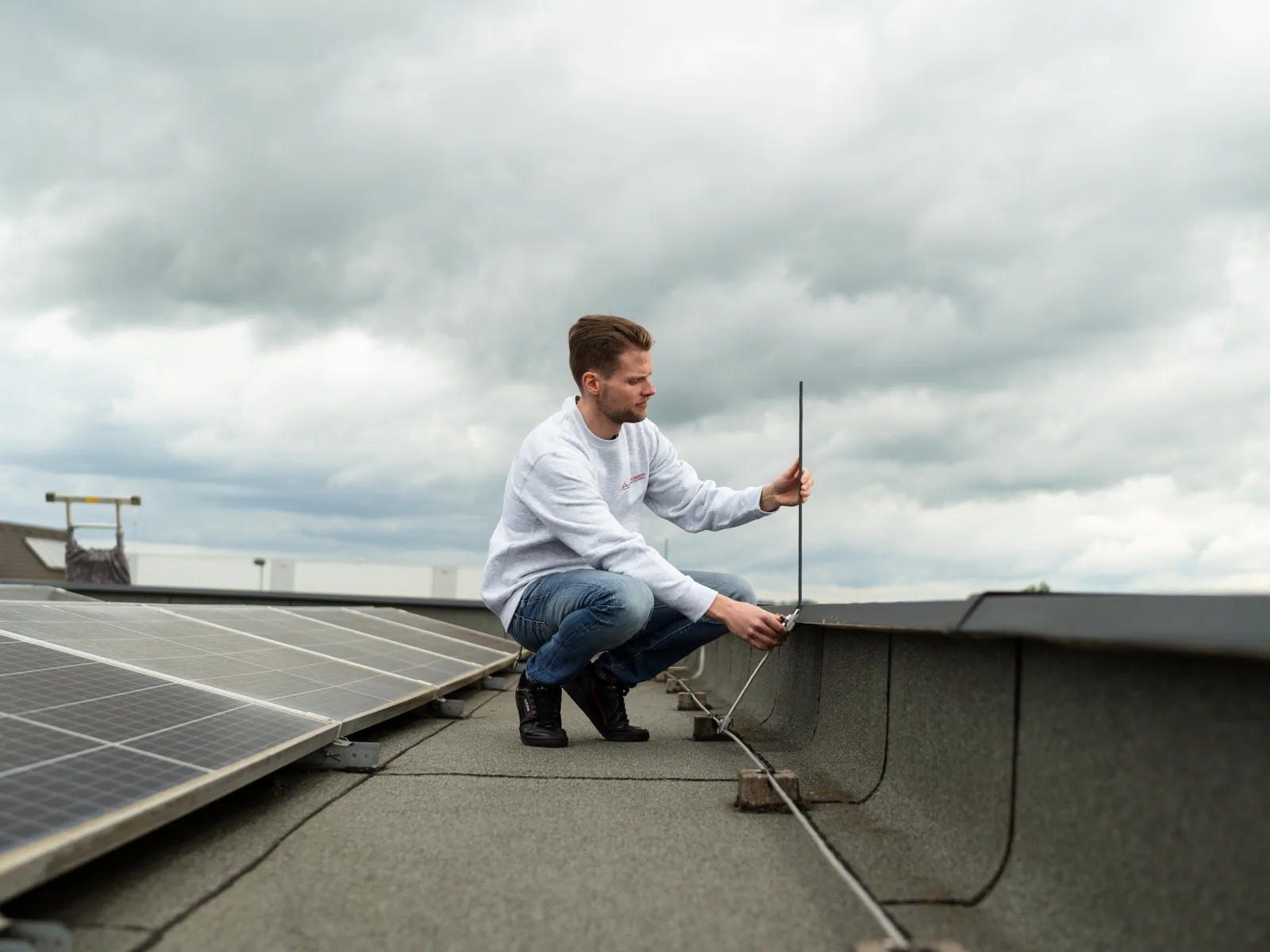 Fangstange neben aufgeständerten Photovoltaikmodulen auf einem Flachdach